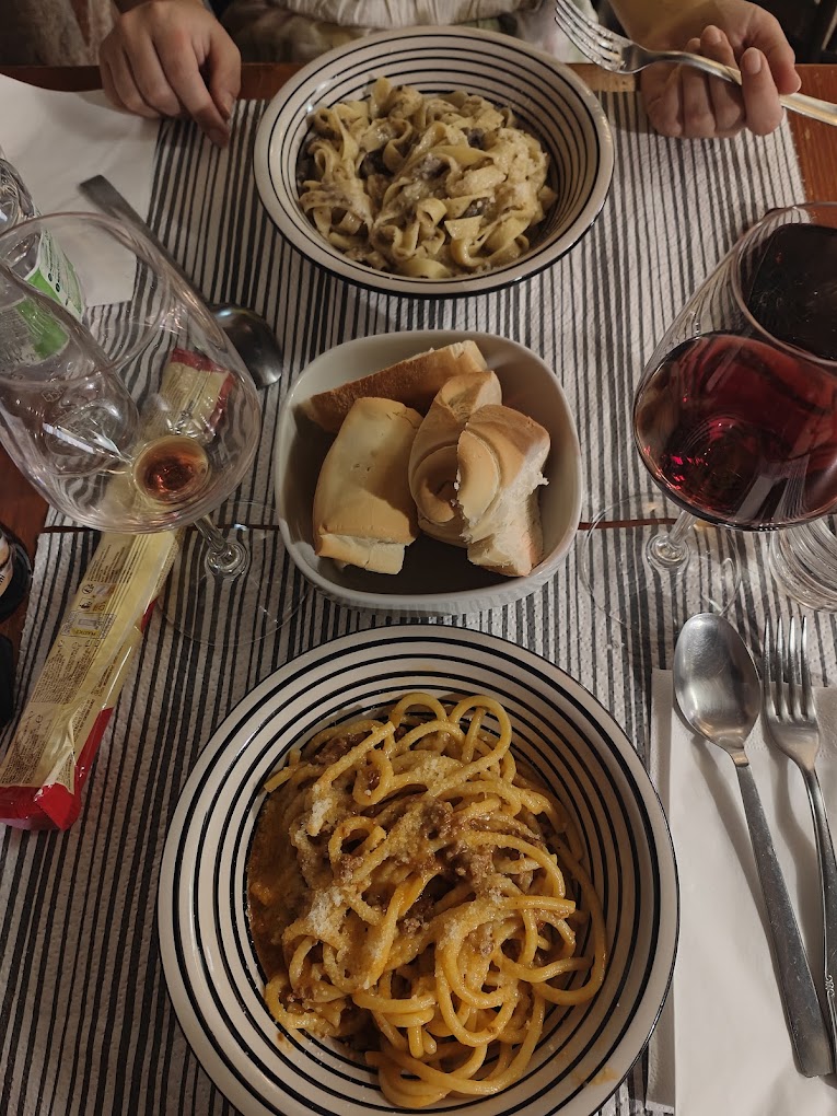 Tagliatelle ai funghi e bigoli al ragù in tavola, con pane e vino rosso